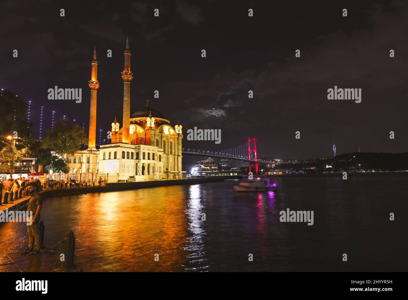 Ortaköy, İstanbul- 20 2021. September: Moschee und Bosporus-Brücke während der blauen Stunde, des Vollmondes und des blauen Nachthimmels. Einer der beliebtesten Orte. Stockfoto