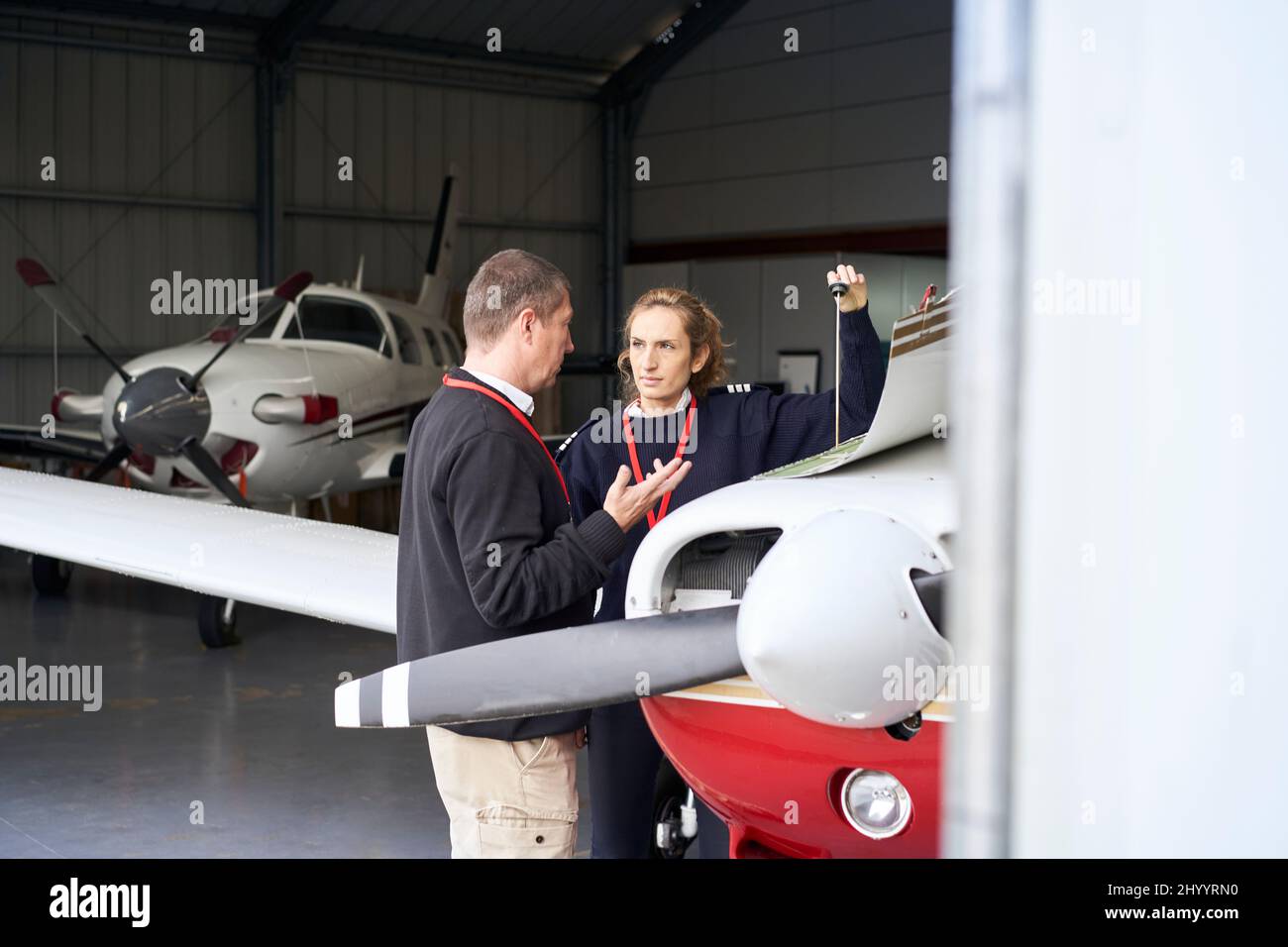 Weibliche Fluglehrerin, die ihrem Schüler beibringt, wie man die Wartung des Flugzeugs macht. Stockfoto