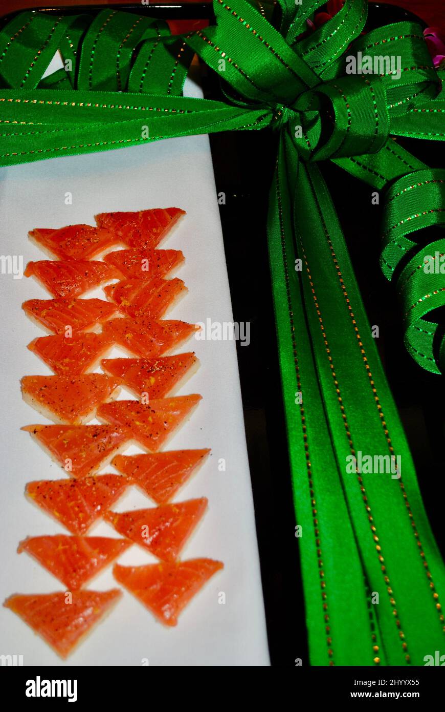 Geräucherter Lachs auf ockerschwanz-Hors d'Oeuvre serviert auf weißem Leinen auf Tablett mit grünem Weihnachtsband Stockfoto