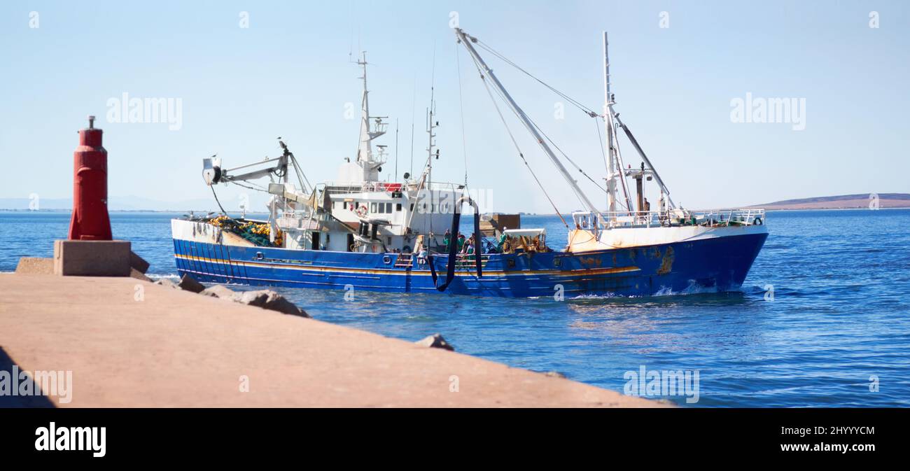 Erster Fang des Tages. Aufnahme eines Fischtrawlers, der den Hafen verlässt. Stockfoto