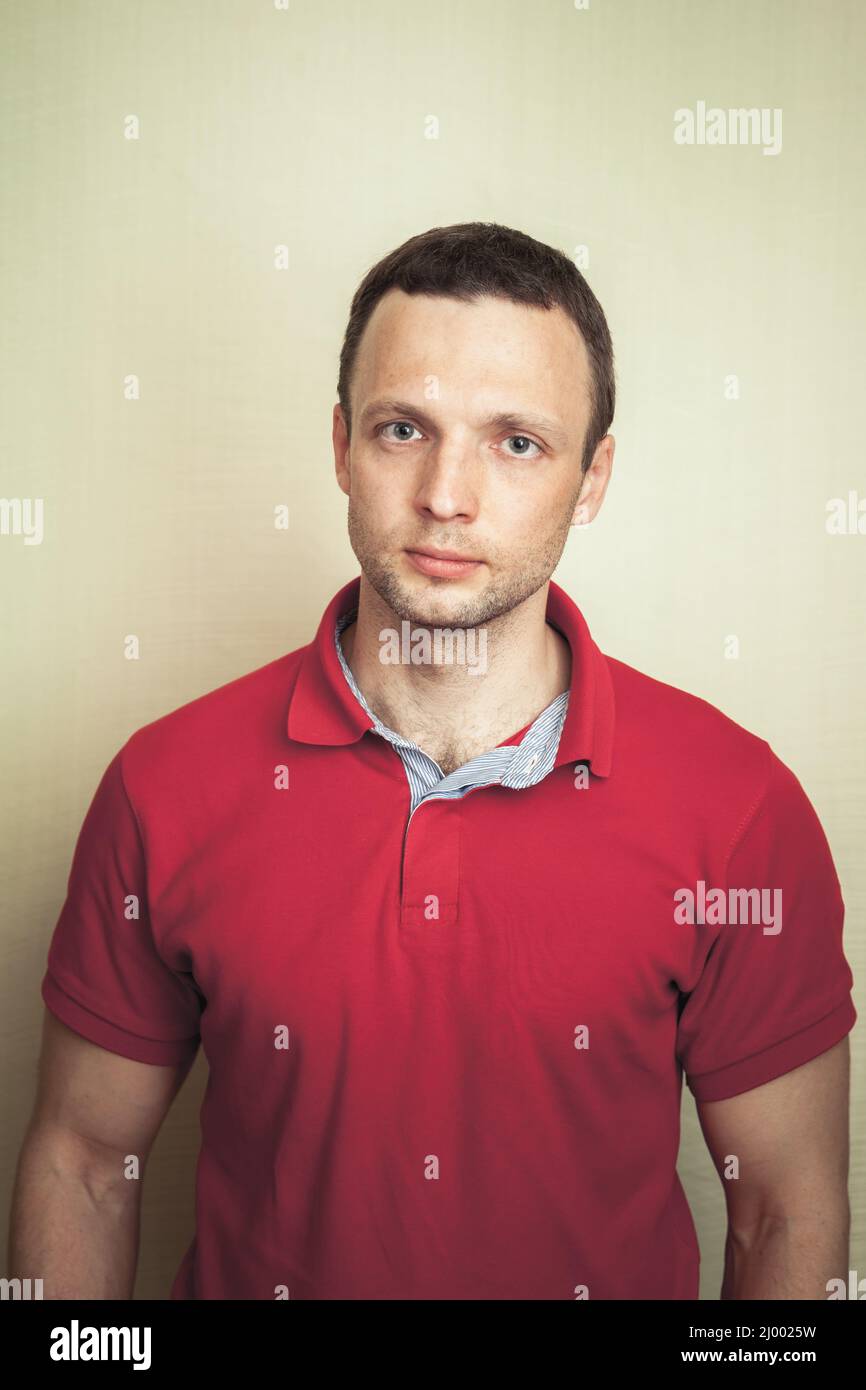 Studioporträt junger Erwachsener europäischer Mann in rotem Poloshirt Stockfoto