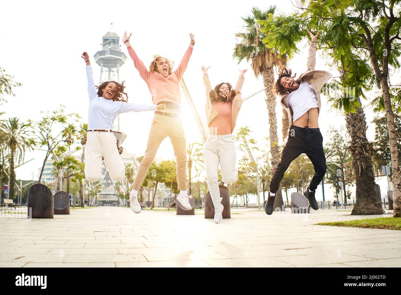 Vier multiethnische Freunde springen vor Freude und feiern Erfolge in der Urlaubsstadt. Stockfoto