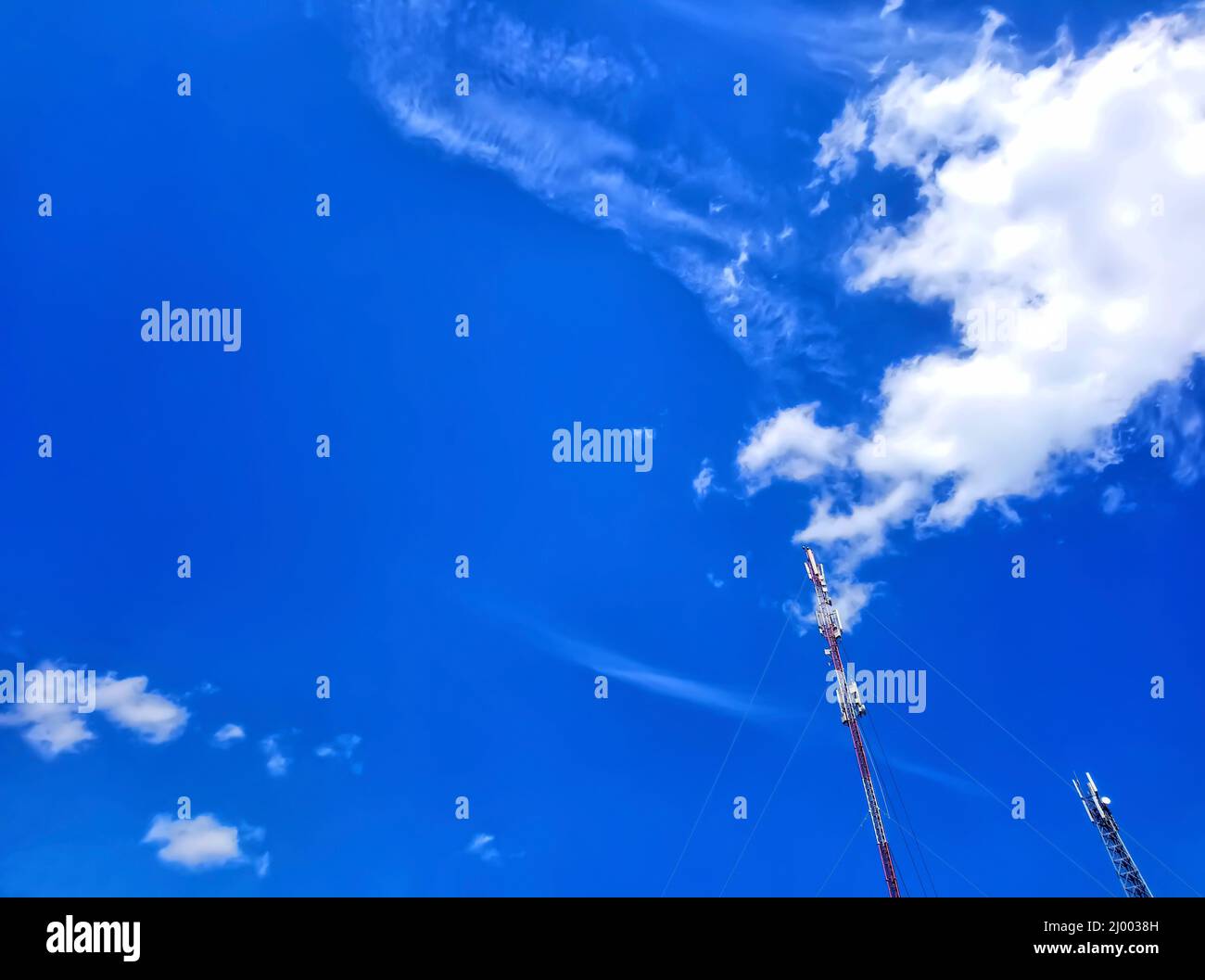 Zwei Antennen, Türme eines Mobilfunkanbieters gegen einen blauen Himmel. Blauer Himmel mit schönen weißen Wolken. Antennen für die mobile Kommunikation, für mobiles Phon Stockfoto