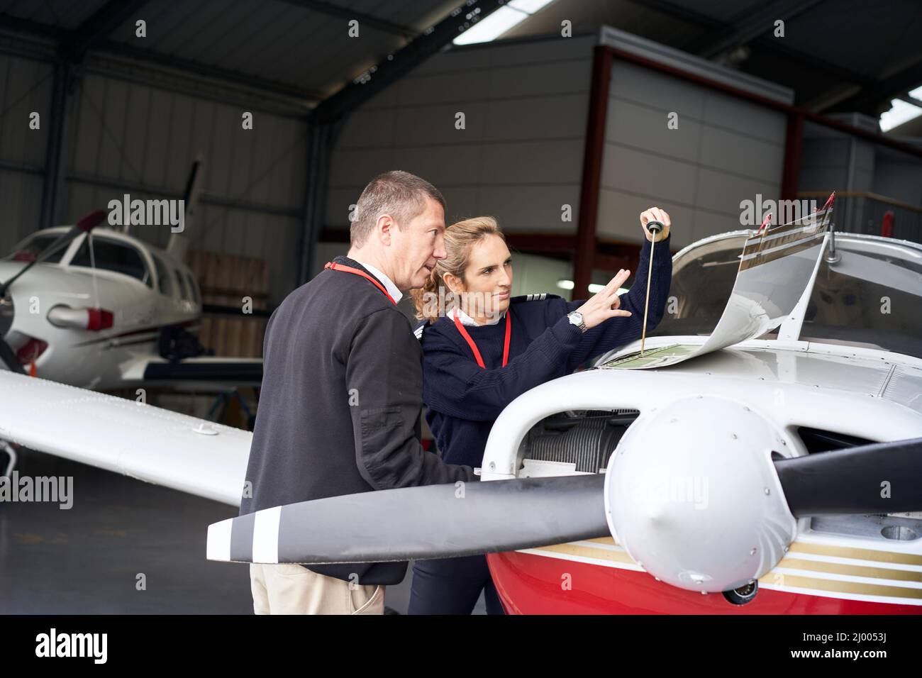 Weibliche Fluglehrerin, die ihrem Schüler beibringt, wie man die Wartung des Flugzeugs macht. Stockfoto