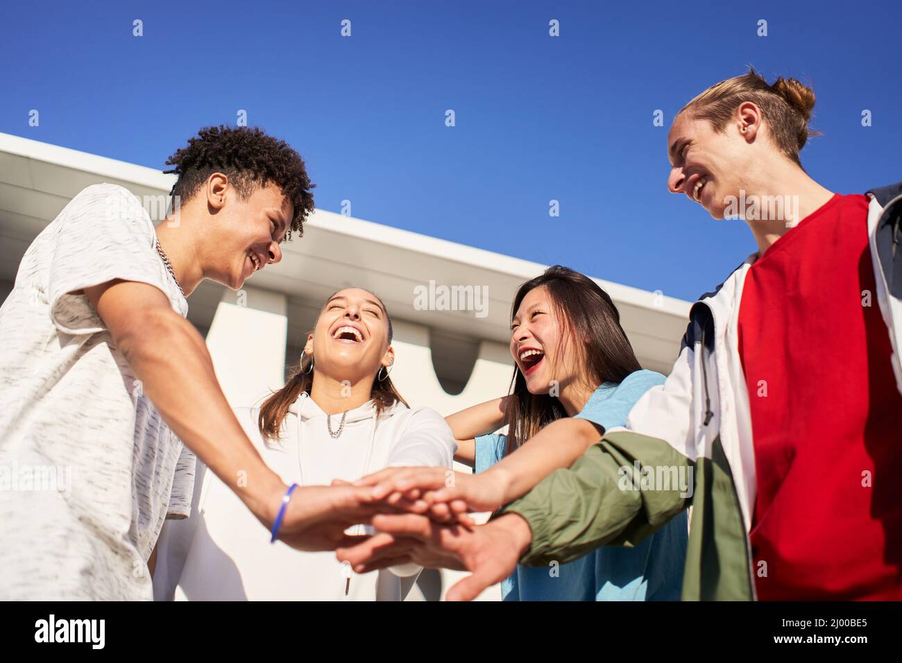 Glückliche junge Freunde, die ihre Hände stapeln. Eine vielfältige Gruppe von Menschen, die gemeinsam feiern und Spaß haben. Stockfoto