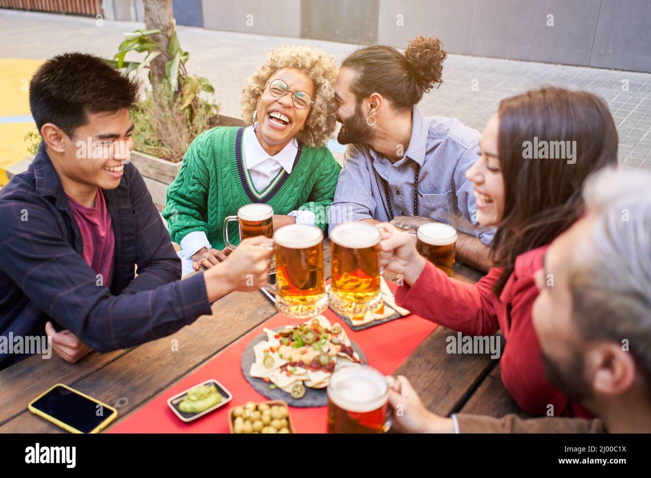 Fröhliche Gruppe von Freunden. Bier toasten. Lächelnde Leute, die sich am Wochenende auf der Partyterrasse amüsieren. Stockfoto