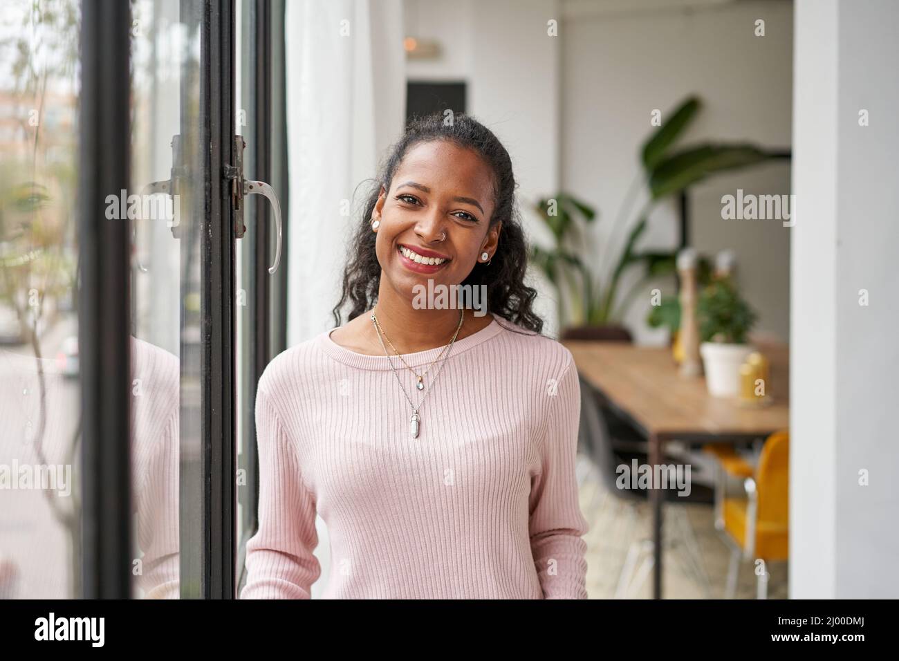 Fröhliche schöne afrikanische Frau professionell zu Hause im Büro mit Blick auf die Kamera. Glückliche selbstbewusste Unternehmerin lachende Gesicht posiert Stockfoto