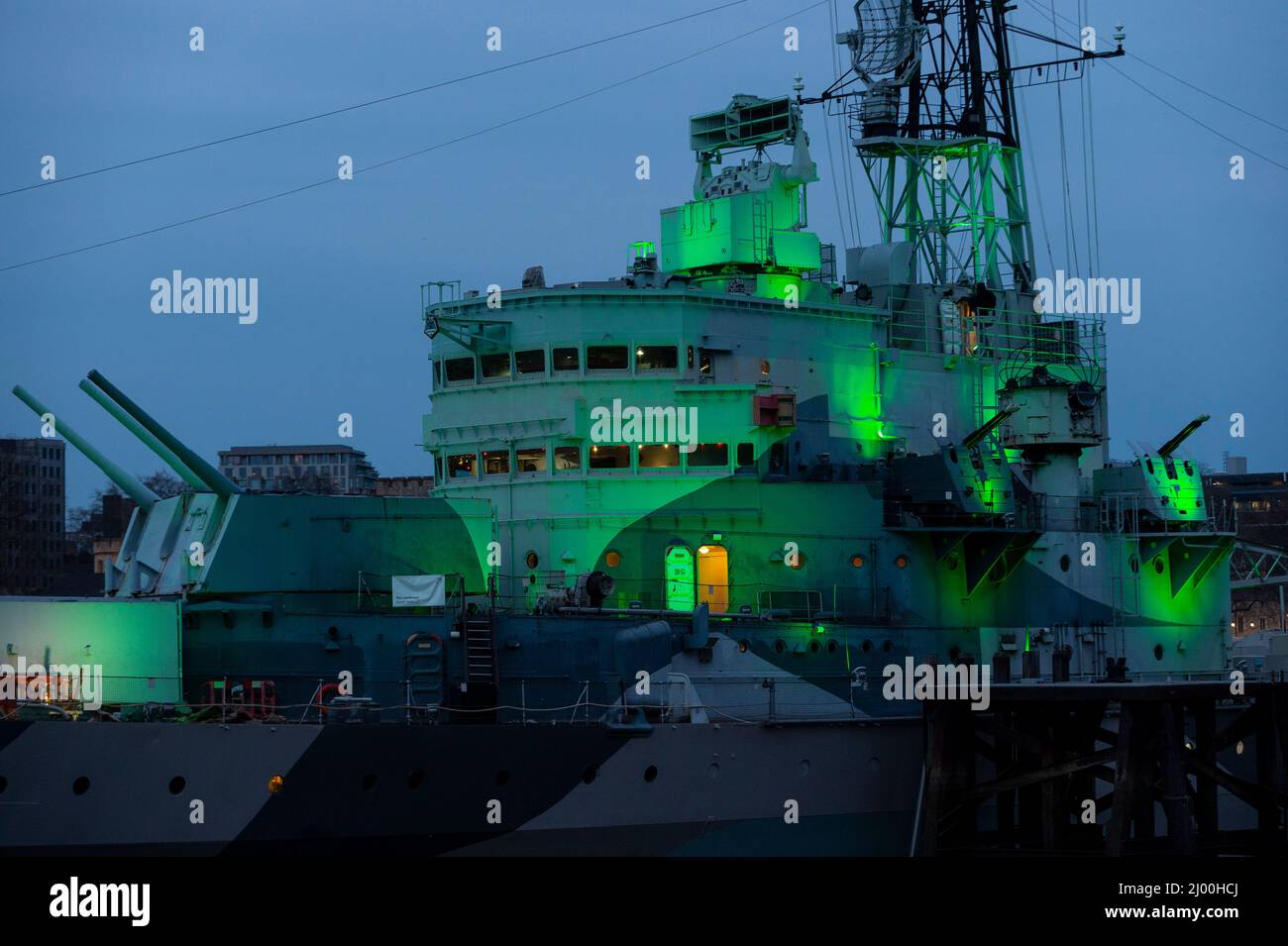 London, Großbritannien. 15. März 2022. Die HMS Belfast ist zum St. Patrick’s Day grün beleuchtet. Das Datum markiert auch den Geburtstag des Schiffes, als es 1938 von der Harland & Wolfe Werft in Belfast gestartet wurde. Sie hat enge Verbindungen mit Irland und ist das erste Schiff, das für die Royal Navy gebaut wurde und nach der Stadt Belfast benannt wurde. Kredit: Stephen Chung / Alamy Live Nachrichten Stockfoto