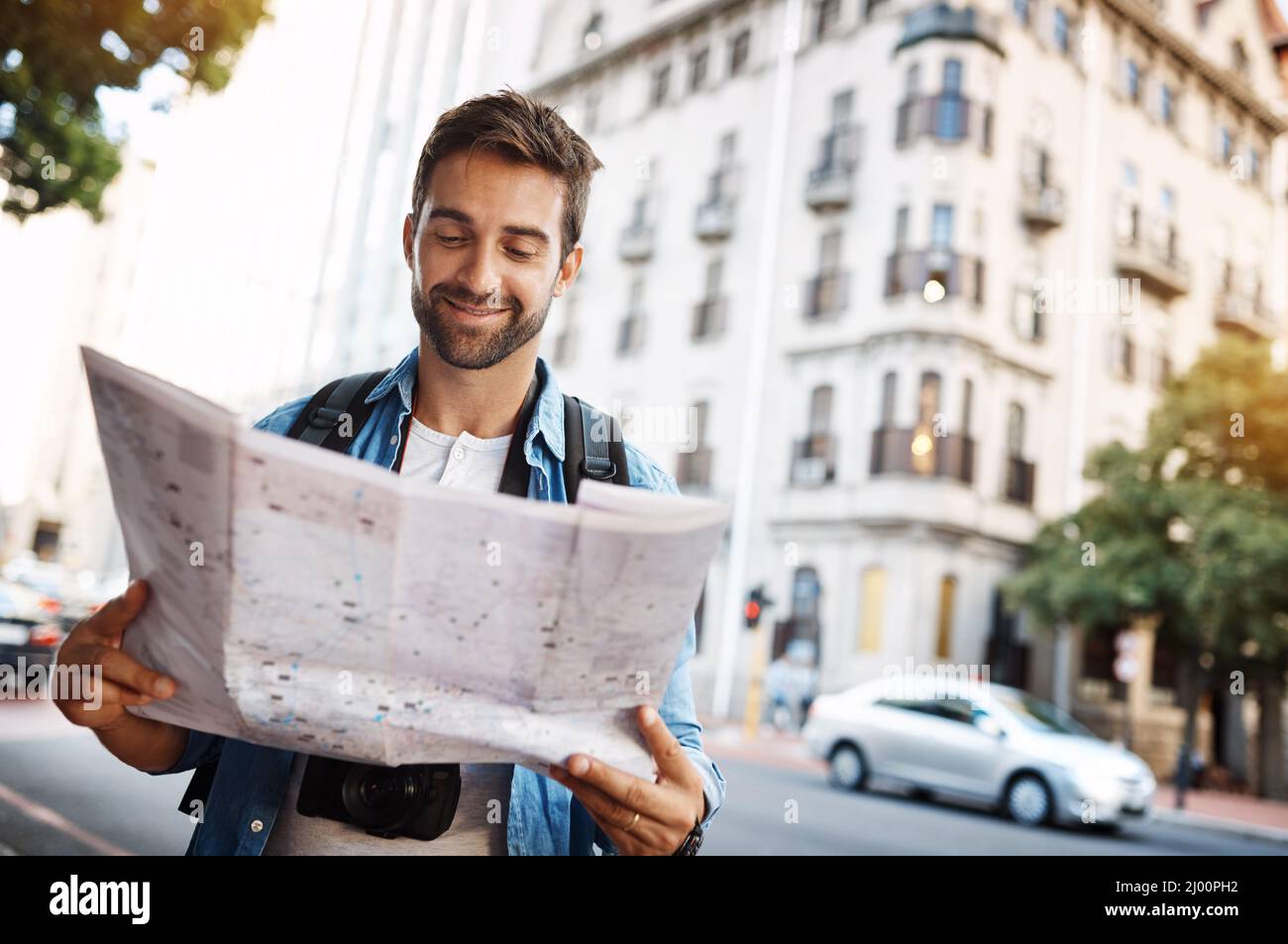 Ich bin genau dort, wo ich sein möchte. Ausgeschnittene Aufnahme eines hübschen jungen Mannes, der auf einer Karte eine fremde Stadt bereist. Stockfoto