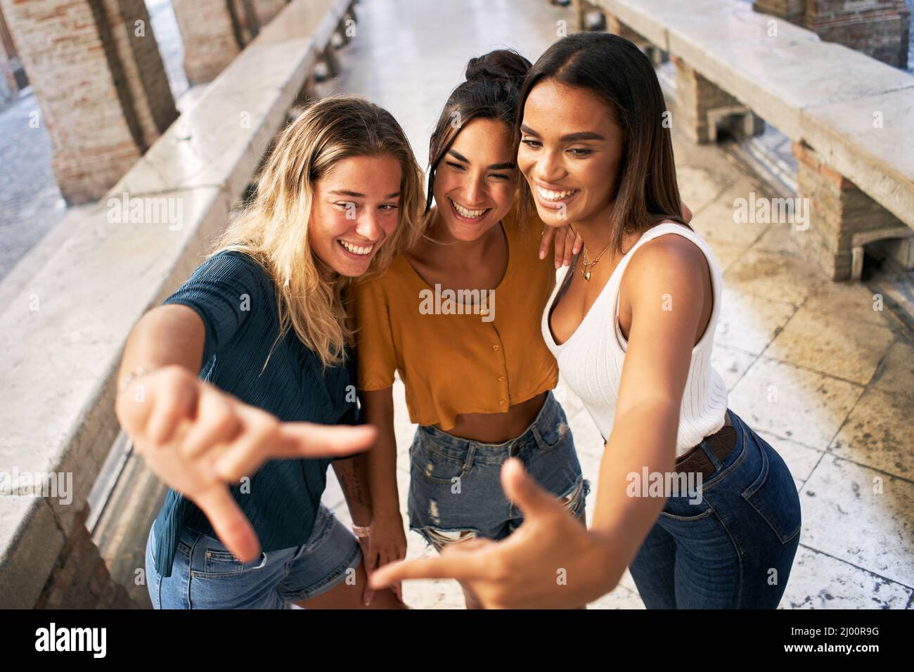 Drei fröhliche Freundinnen in Sommerkleidung, die ein Selfie im Freien in der touristischen Stadt im Stadtzentrum machen Stockfoto