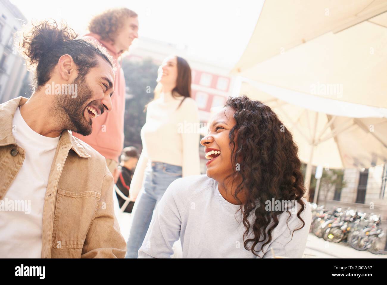 Heterosexuelle Paare flirten draußen auf der Terrasse einer Bar. Multirassische Gruppe von Jungs und Mädchen treffen sich durch Dating-Apps Stockfoto
