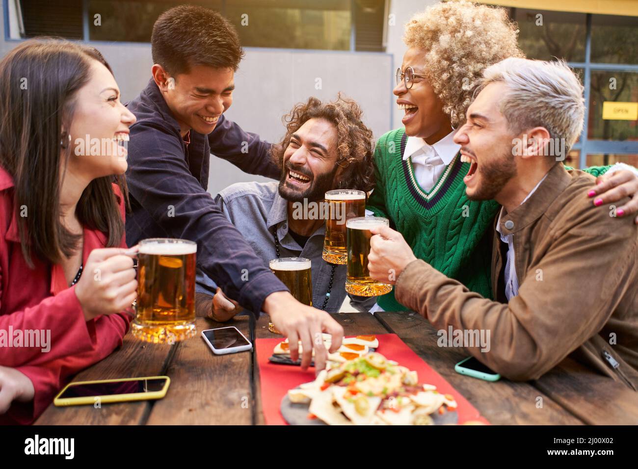 Eine Gruppe von Freunden genießt abends Getränke und Essen in der Bar. Fröhliche Menschen, die lachen Stockfoto