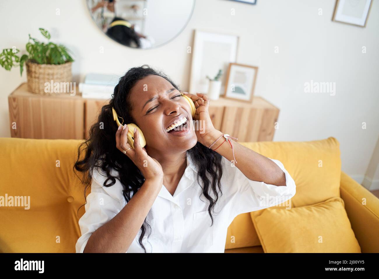 Motivierte junge Frau, die mit einem digitalen Tablet Musik hört, während sie zu Hause auf dem Sofa sitzt. Stockfoto
