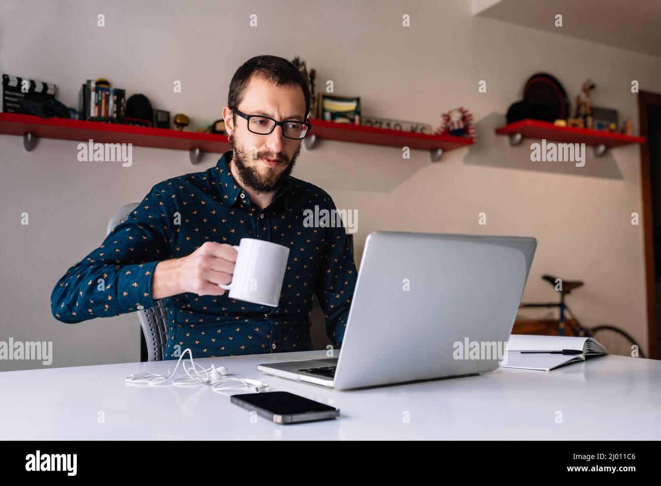 Mann, der während der Telearbeit einen Kaffee getrunken hat Stockfoto