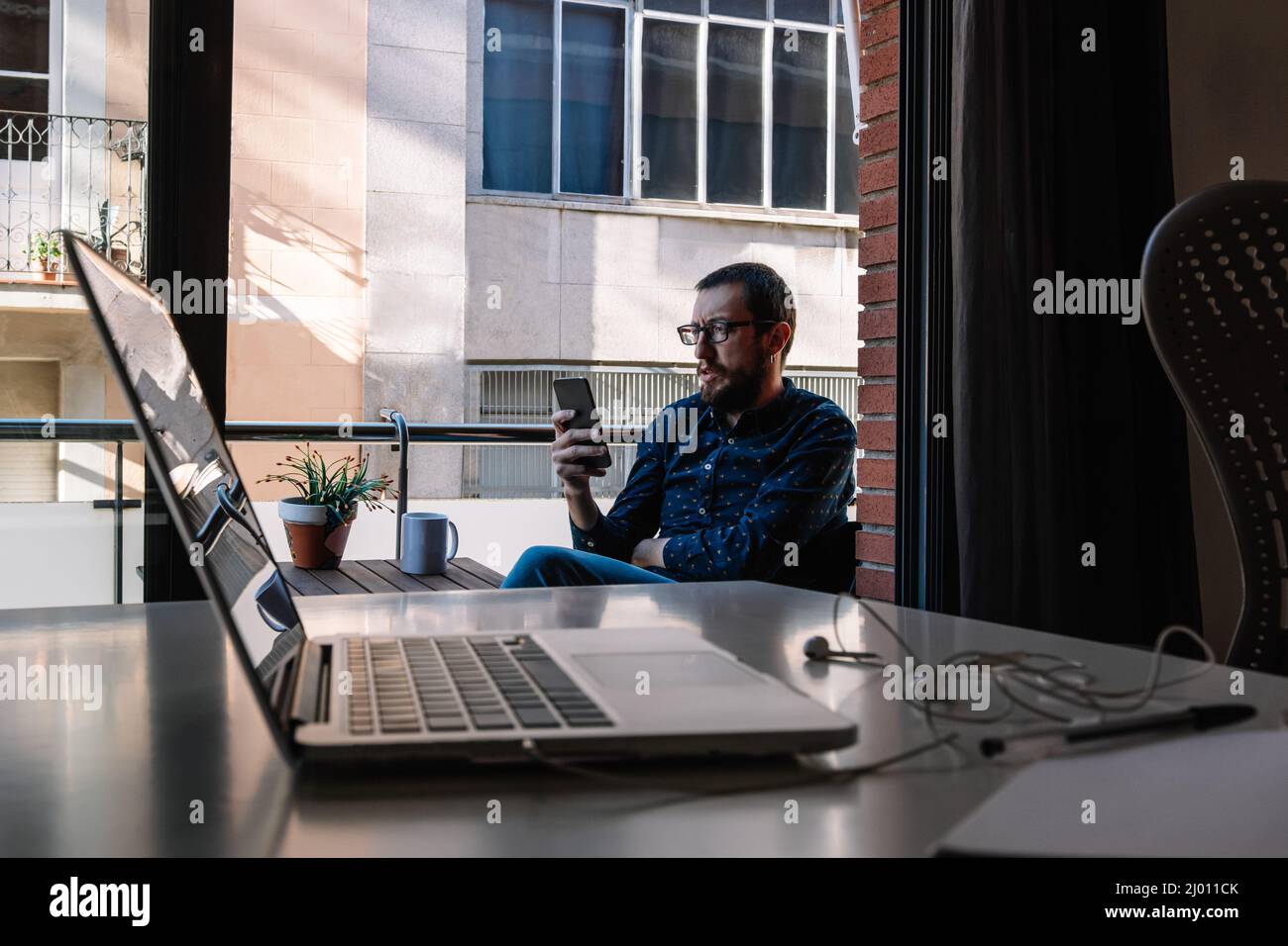 Mann macht eine Pause von der Telearbeit, indem er sein Smartphone anschaut Stockfoto