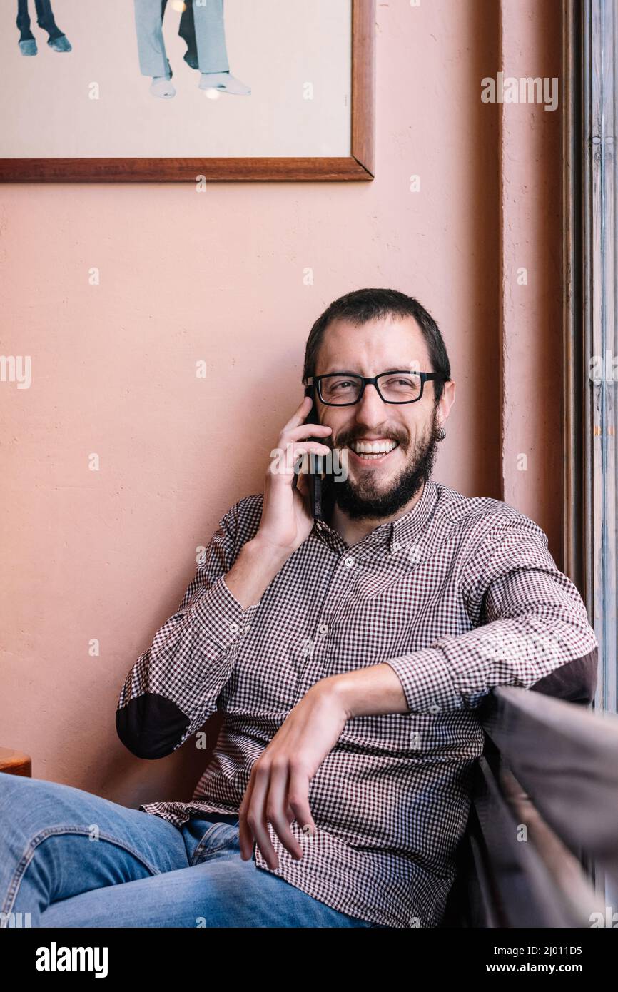 Junger kaukasischer Mann lächelt glücklich im Gespräch auf dem Smartphone Stockfoto