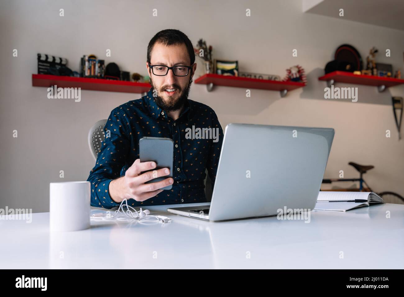 Mann überprüft während der Telearbeit sein Telefon Stockfoto