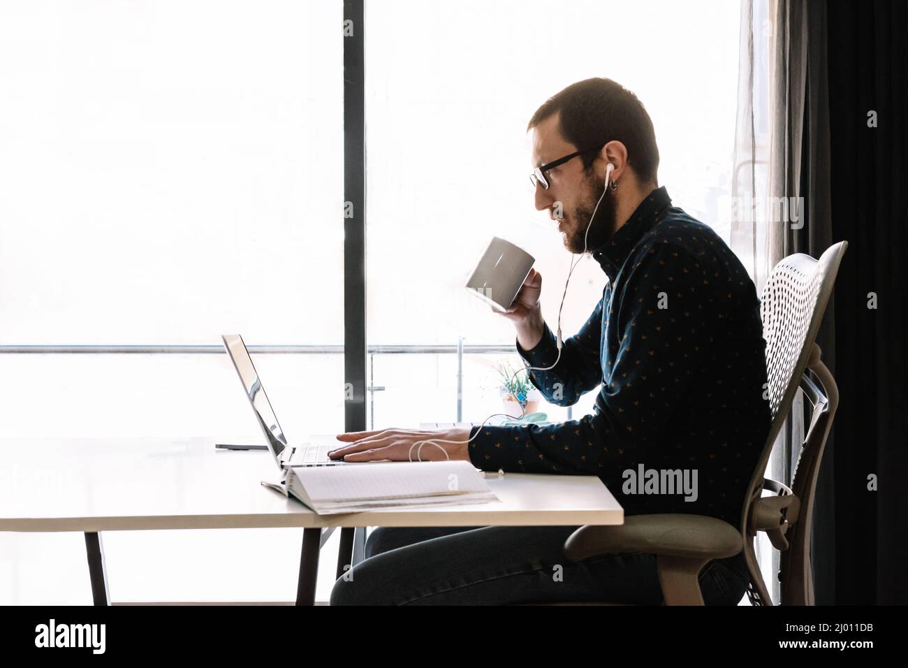 Mann, der während der Telearbeit einen Kaffee getrunken hat Stockfoto