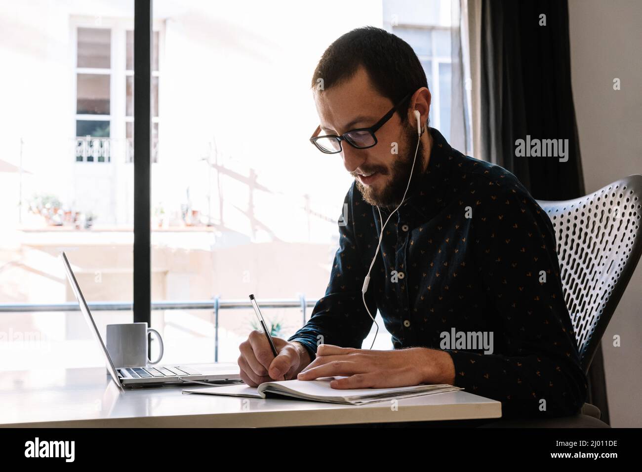 Mann, der zu Hause arbeitet und seinen Aktionsplan aufschreibt Stockfoto