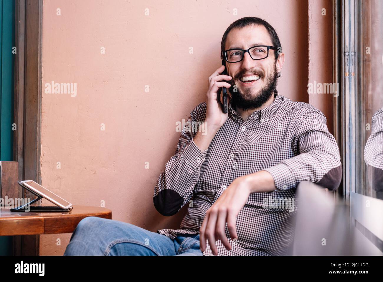 Junger kaukasischer Mann lächelt glücklich im Gespräch auf dem Smartphone Stockfoto