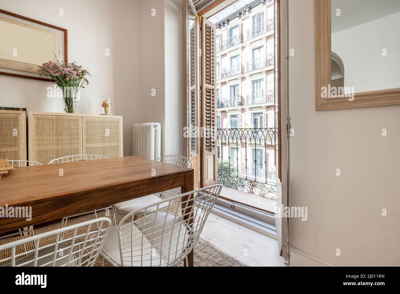 Esstisch aus Holz mit Metallstühlen und Balkon mit Blick auf die Straße Stockfoto