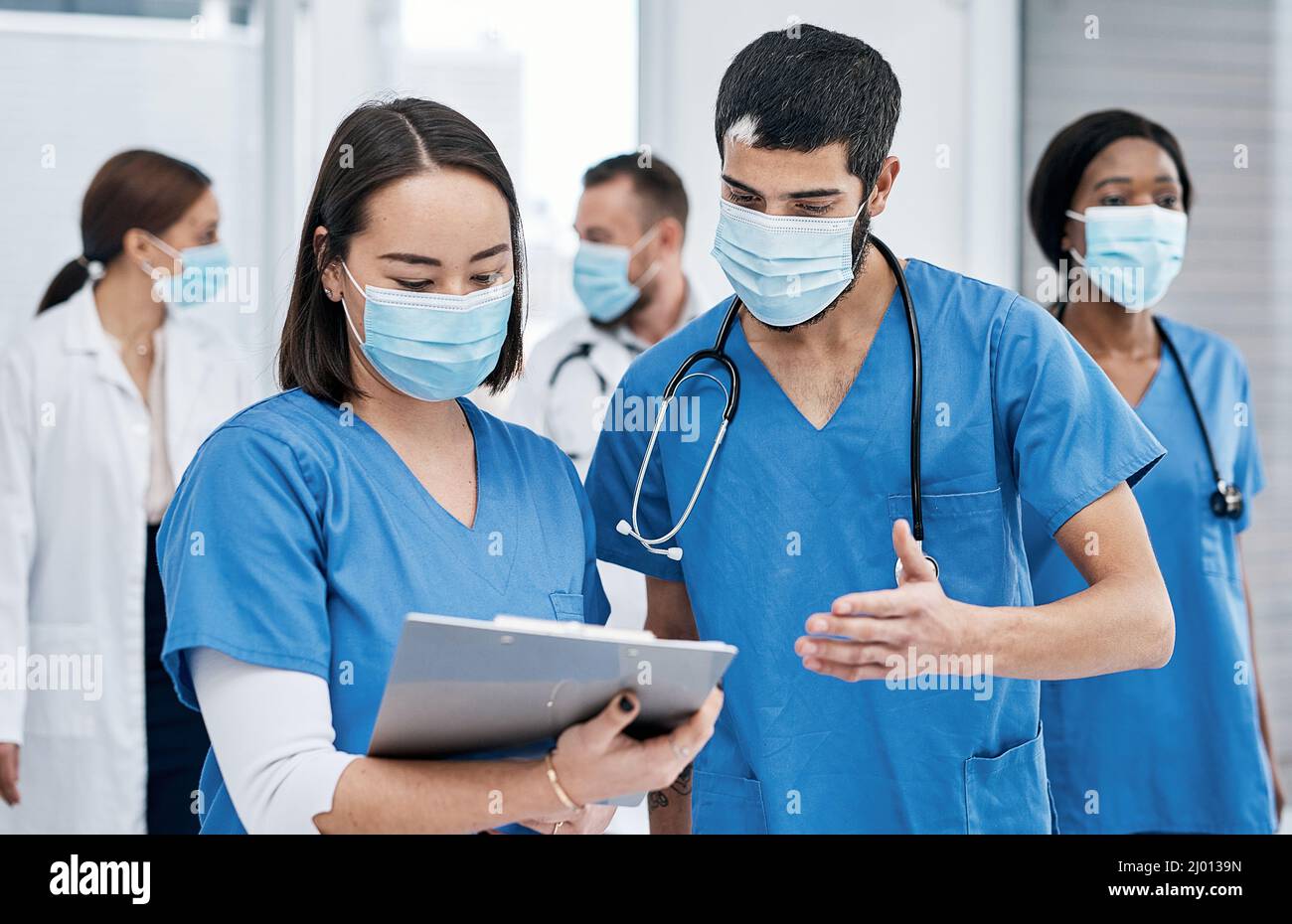 Besprechen, was als Nächstes zu tun ist. Aufnahme von zwei Ärzten, die in einem geschäftigen Krankenhaus Notizen durchgingen. Stockfoto