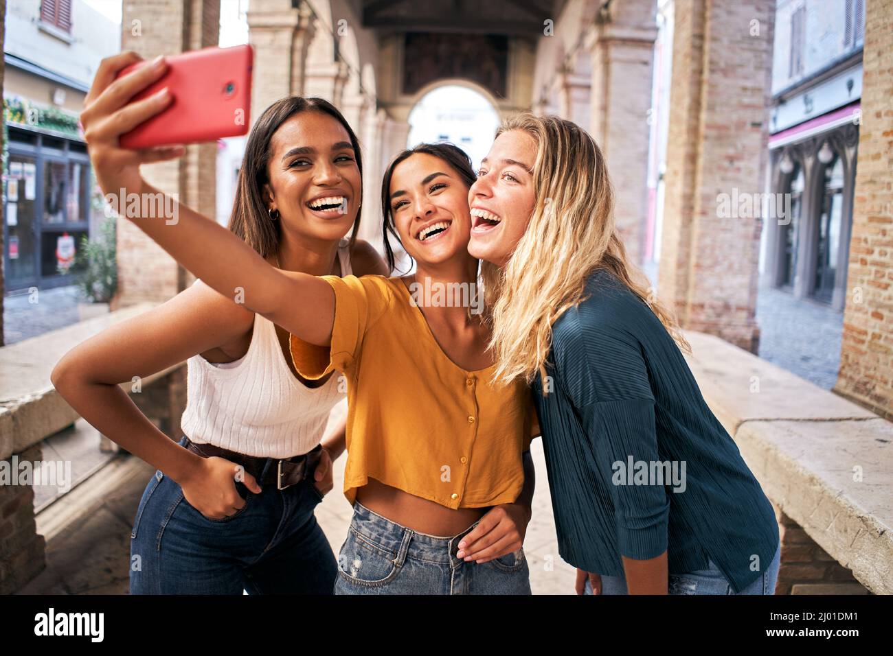 Drei fröhliche Freundinnen in Sommerkleidung, die ein Selfie im Freien in der touristischen Stadt im Stadtzentrum machen Stockfoto