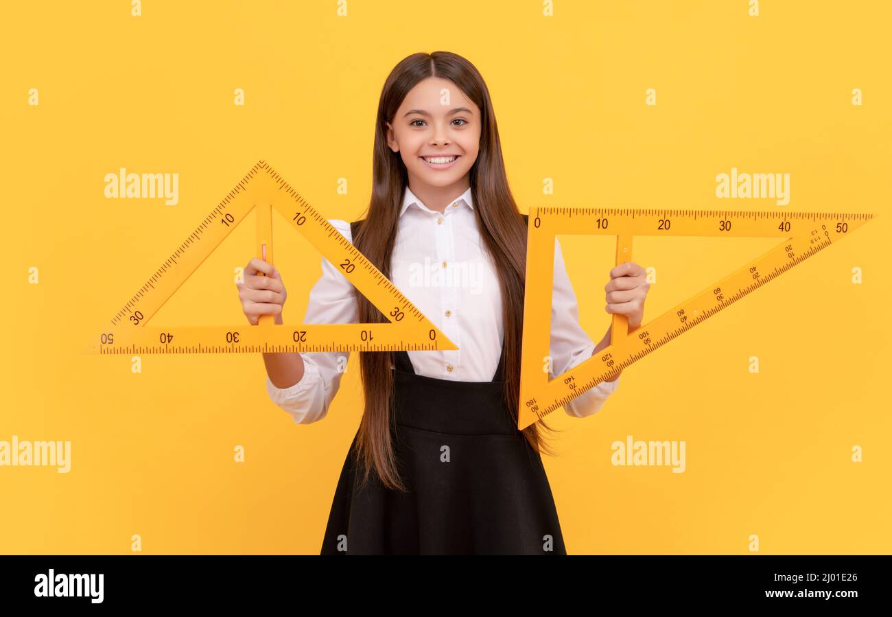 Lächelndes Teenager-Mädchen halten Dreieck. Zurück zur Schule. Algebra und Geometrie. Kind Mathematik lernen. Stockfoto