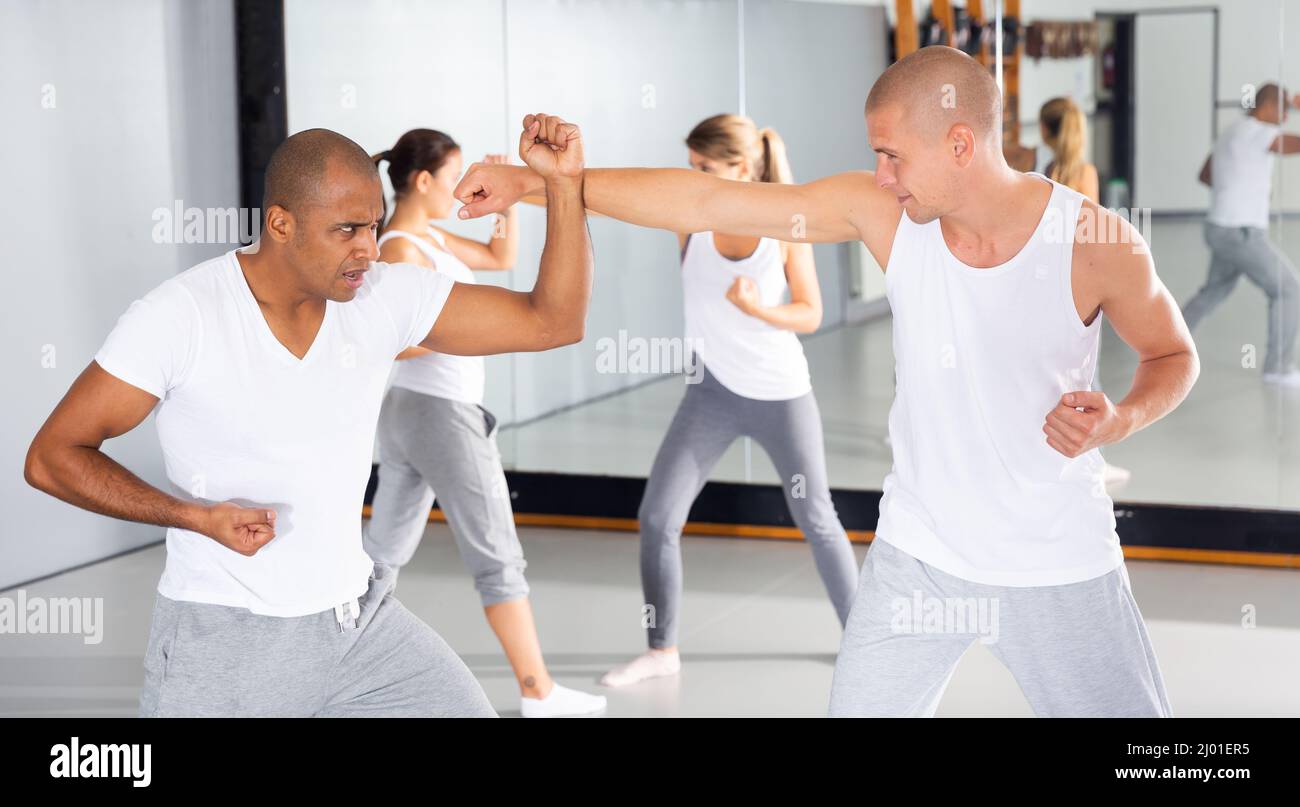 Männer üben grundlegende Bewegungen während des Selbstverteidigungskurses im Fitnessstudio Stockfoto