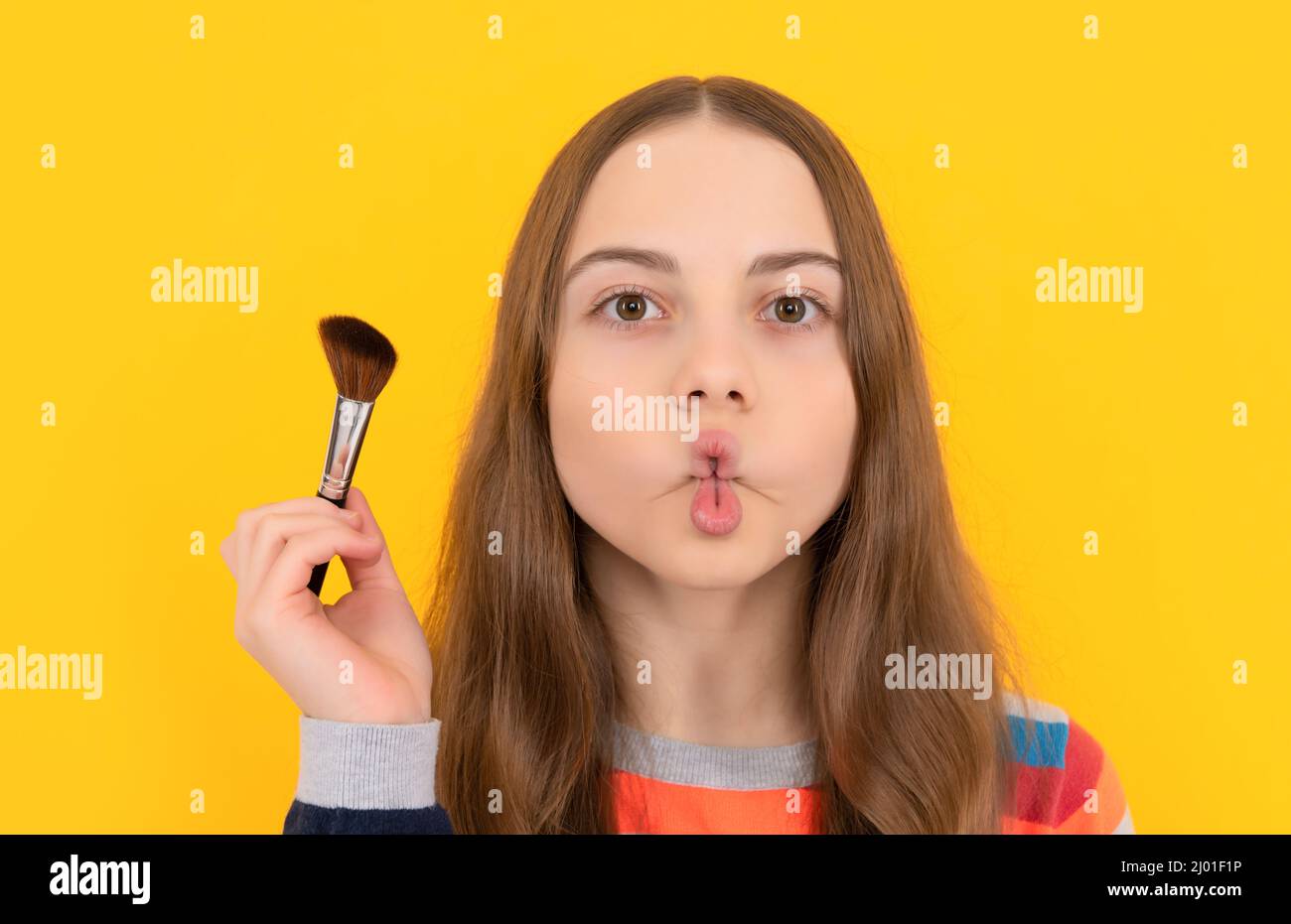 Porträt von Kind, das lustige Fischlippen Gesicht hält Puderbürste für die Anwendung von Kosmetik, Make-up Stockfoto