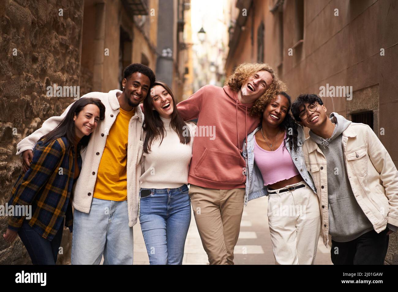 Eine Gruppe von Zwanzigern, die auf der Straße auf die Kamera schauen. Glücklich lächelnde Freunde umarmen Stockfoto