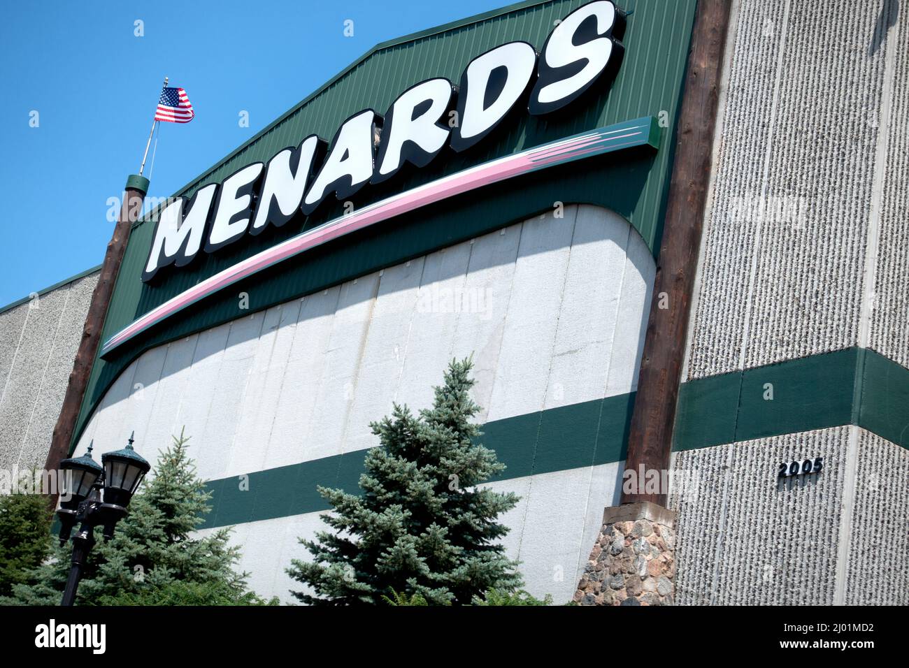 Menards Store für Heimwerkerbedarf und Baumaterialien, die die amerikanische Flagge führen, mit Evergreens auf der vorderen Terrasse. Blaine Minnesota, USA Stockfoto