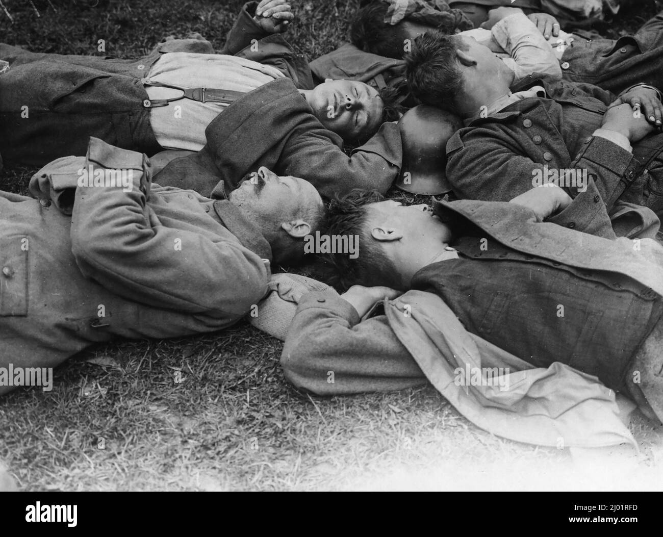 Dieses Bild zeigt eine Gruppe deutscher Gefangener. Sie liegen alle auf dem Boden und scheinen zu schlafen. Ein Soldat benutzt seinen Helm als Kissen. Stockfoto