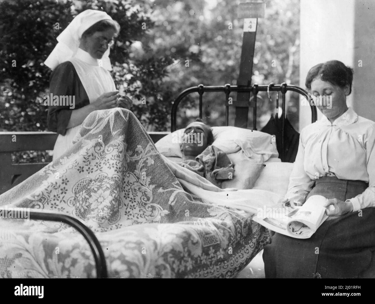 Verwundete Soldaten liegen in einem Krankenhausbett. Er wird von einer Krankenschwester betreut. Nach der Originalunterschrift ist die rechts sitzende Frau seine Mutter. Stockfoto