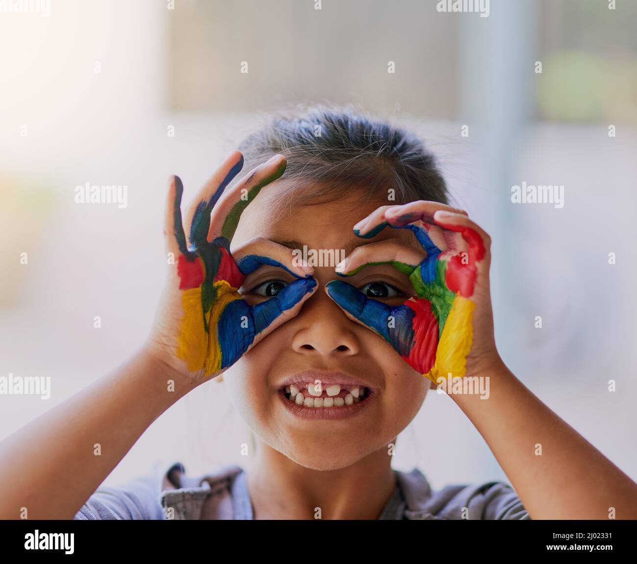 Kinder haben die kreativsten Arten, die Welt zu betrachten. Porträt eines kleinen Mädchens mit ihren Händen bedeckt mit Farbe. Stockfoto