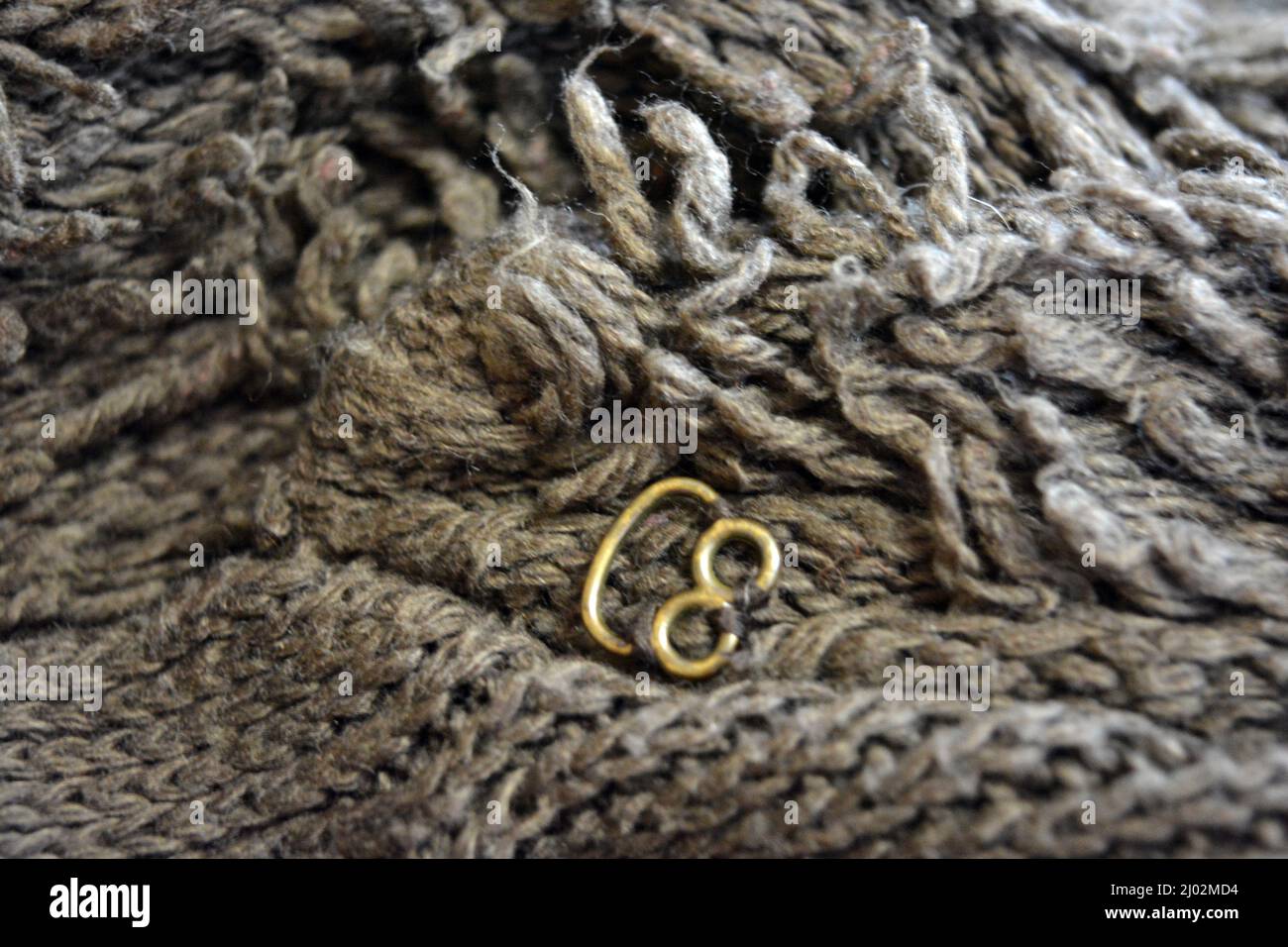 Damenbekleidung, stylische Strickwaren aus Braun, Oliv, Dunkelbeige, Naturwolle, dichten Garnen und dunkelgoldenen Haken, Riegel. Stockfoto