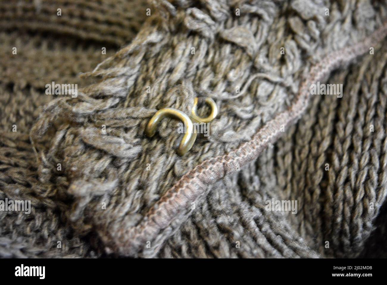 Damenbekleidung, stylische Strickwaren aus Braun, Oliv, Dunkelbeige, Naturwolle, dichten Garnen und dunkelgoldenen Haken, Riegel. Stockfoto