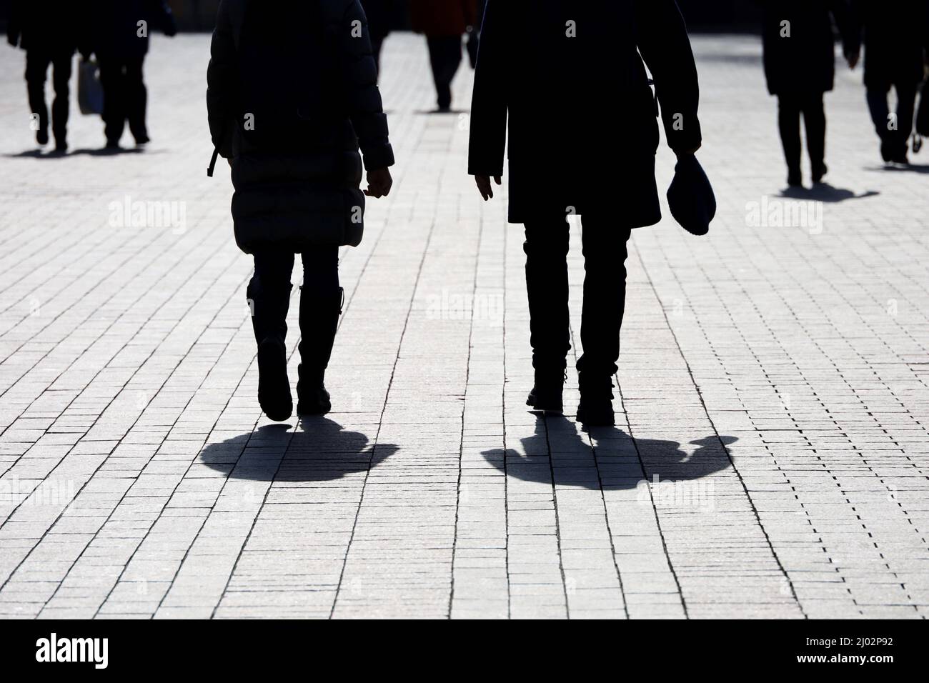 Silhouetten und Schatten von Menschen auf der Straße der Stadt. Menschenmenge, die auf dem Bürgersteig, dem Konzept von Fremden, Kriminalität, Gesellschaft oder Bevölkerung hinuntergeht Stockfoto