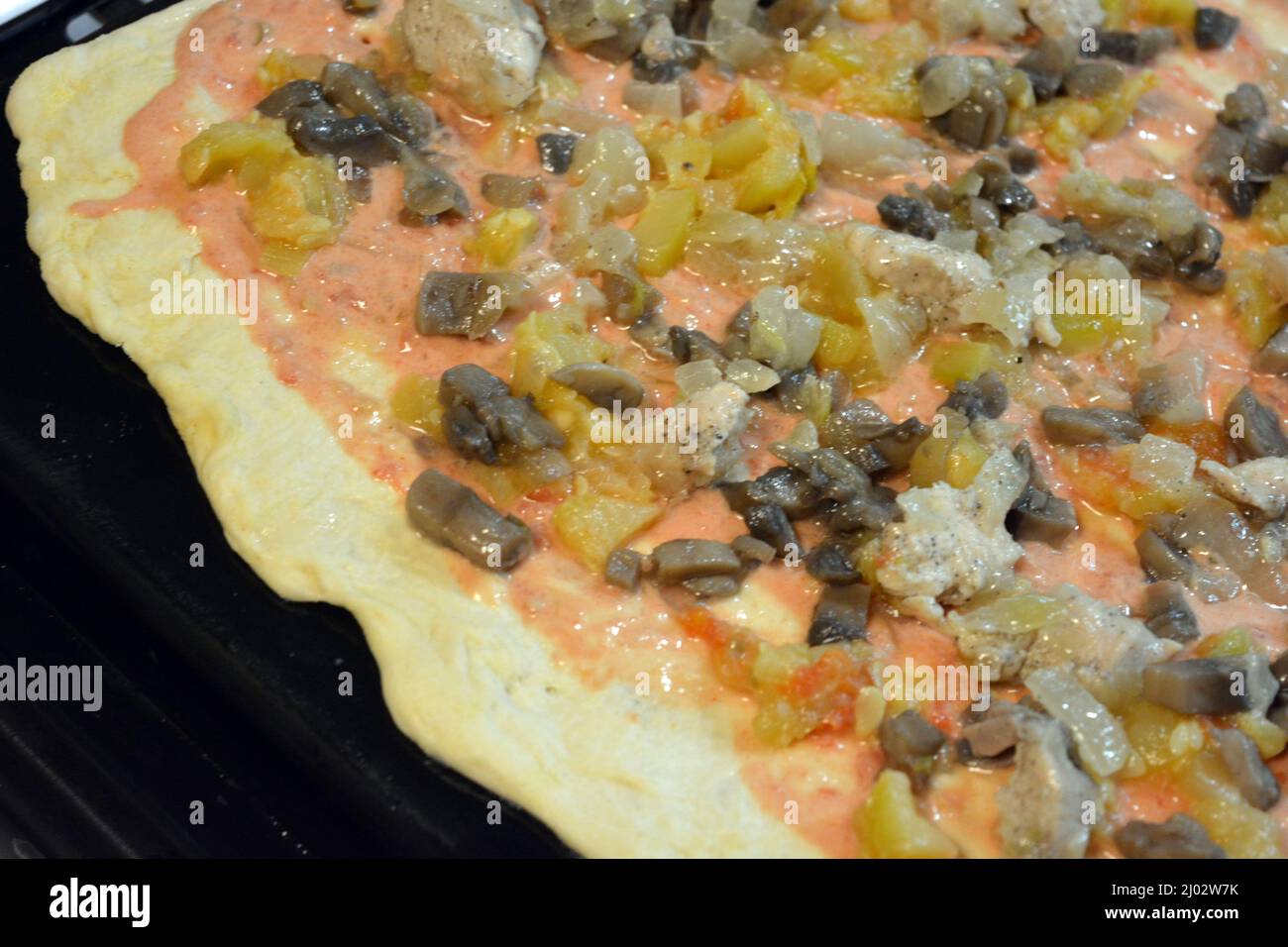 Küche, kochen köstliche Mahlzeiten. Eine große hausgemachte Pizza mit Fleisch, Pilzen, Ananas und Käse auf einem großen Blechblech. Stockfoto