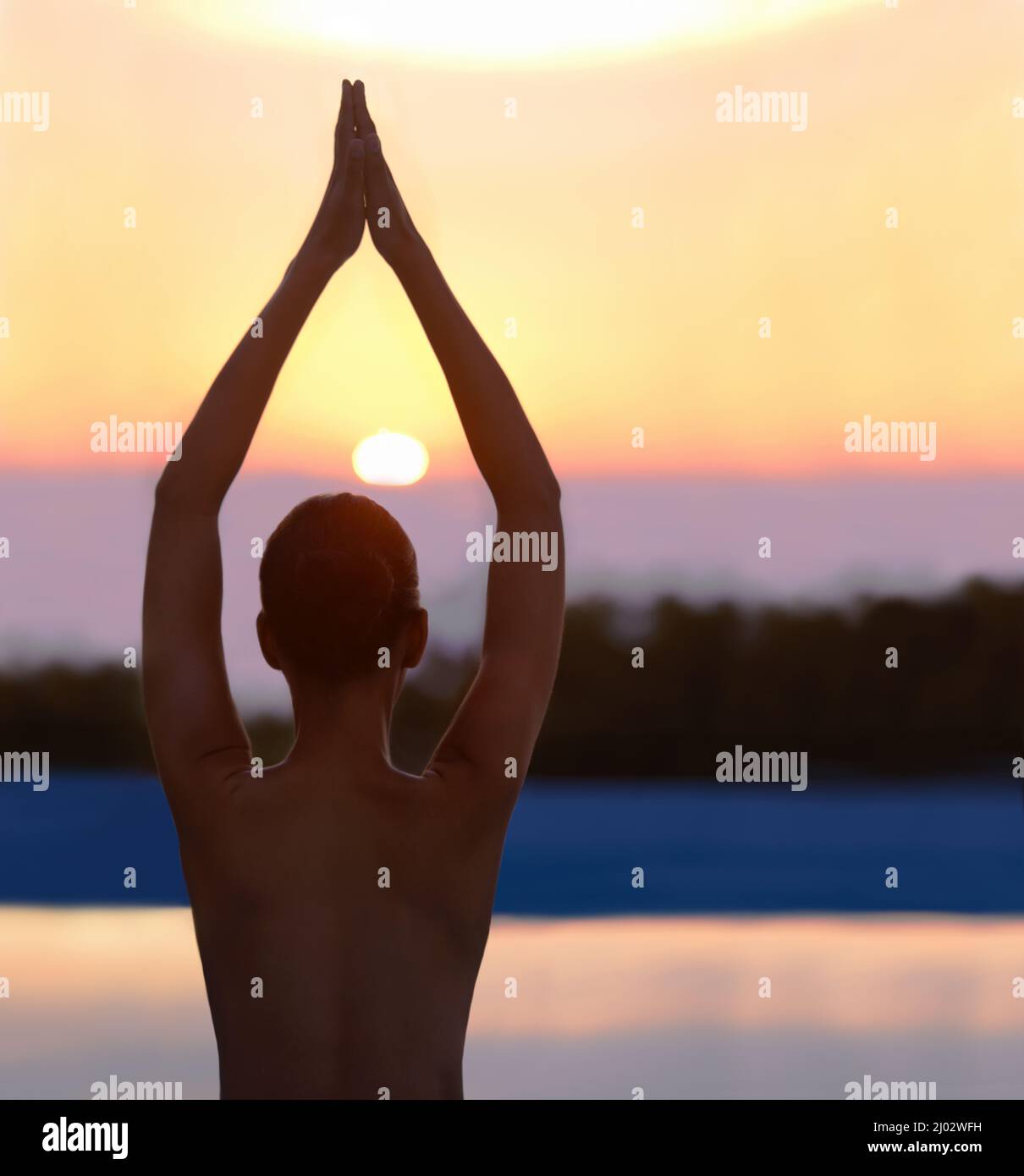 Ruhe in der Natur finden. Eine schöne junge Frau in einer Yoga-Pose bei Sonnenuntergang. Stockfoto