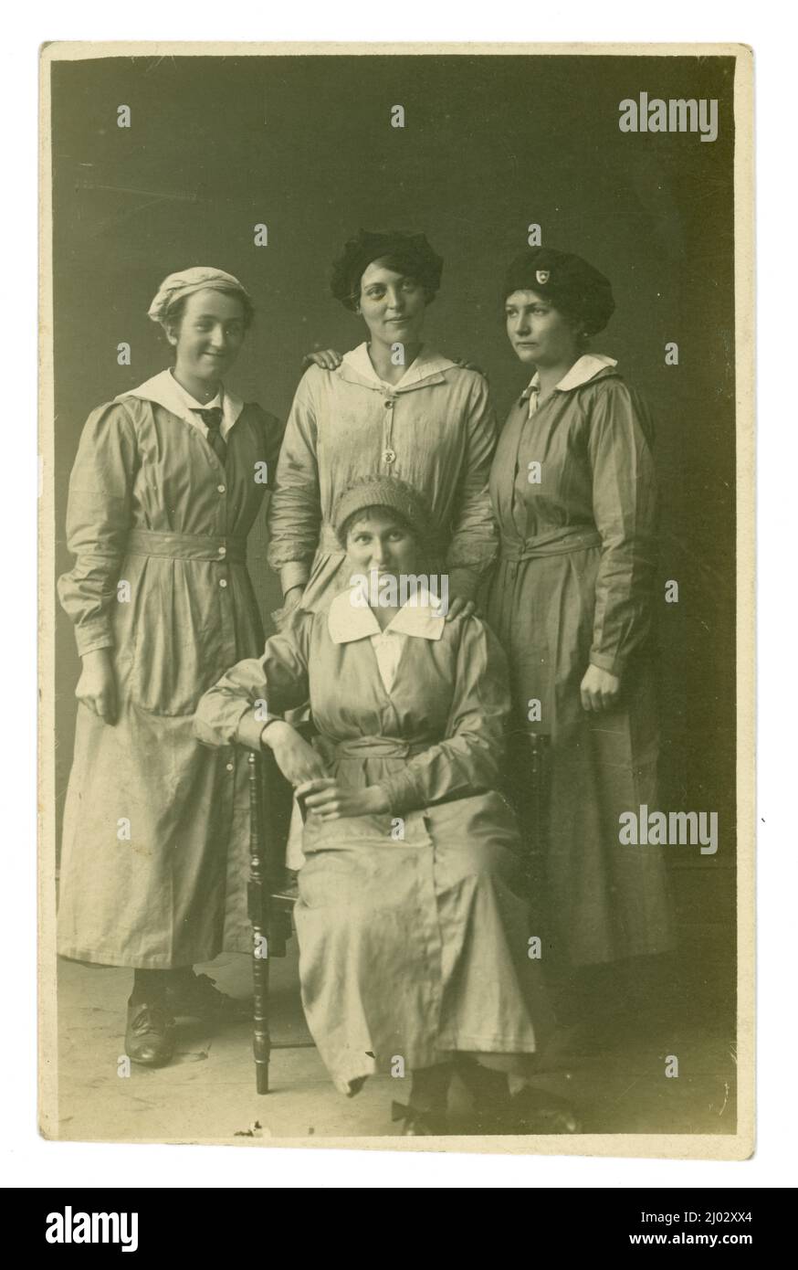 Originalpostkarte aus dem Jahr WW1 von 4 Arbeiterinnen, möglicherweise Munitionsarbeiterinnen, Fabrikarbeitern, 2 tragen das gleiche Mützenabzeichen (aber es handelt sich nicht um das übliche Abzeichen zum Kriegsdienst, das von vielen Munitionsarbeitern getragen wird), um 1916, Großbritannien Stockfoto
