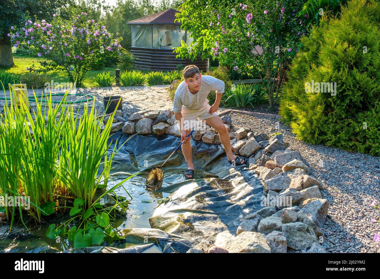 Teenager Reinigung Teich mit Landungsnetz Stockfoto