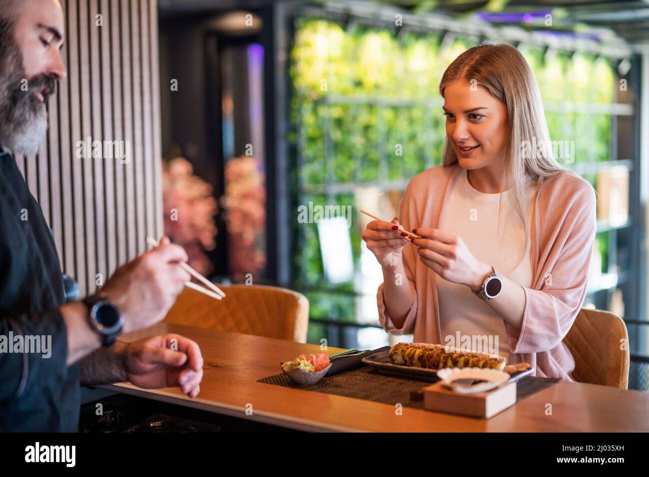 Sushi-Meister lehrt junge Frauen, wie man Essstäbchen im Sushi-Restaurant verwendet. Stockfoto