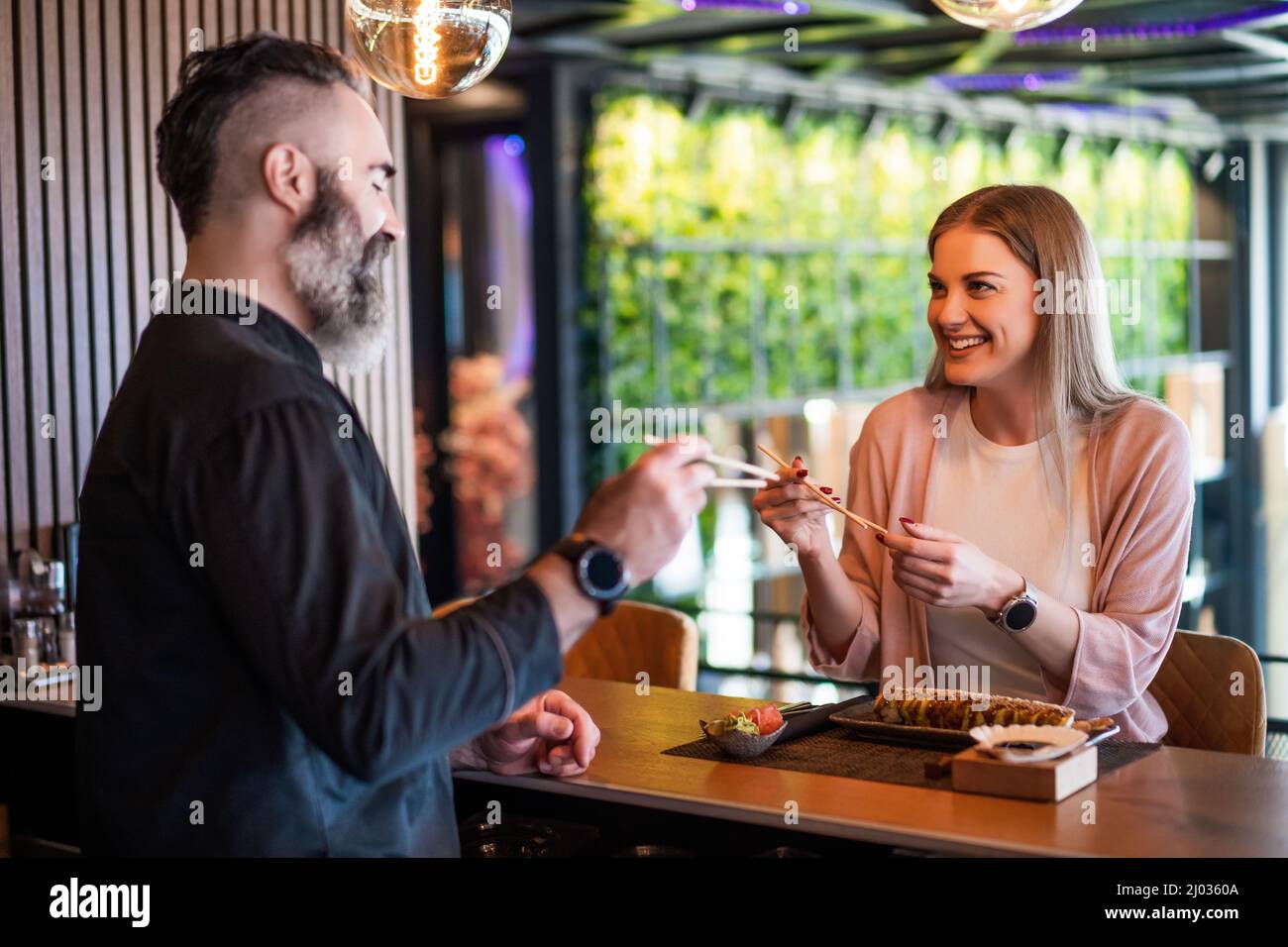 Sushi-Meister lehrt junge Frauen, wie man Essstäbchen im Sushi-Restaurant verwendet. Stockfoto