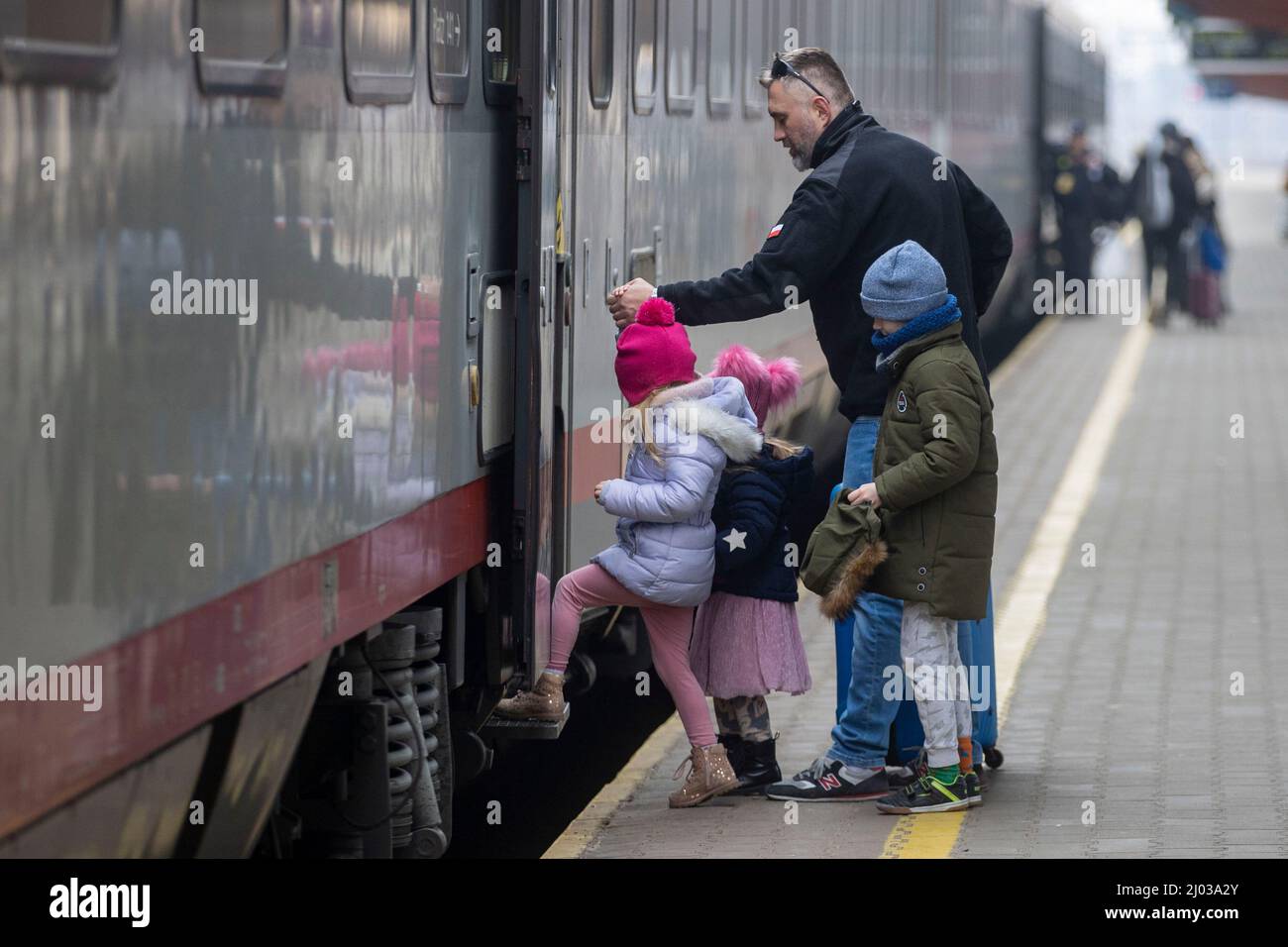 Przemysl, Polen. 16. März 2022. Auf dem Bahnsteig im Bahnhof Przemaysl warten Flüchtlinge auf ihre Weiterreise, ein Helfer der polnischen Armee hilft drei Kindern in den Zug nach Graz in Österreich. Quelle: Christoph Reichwein/dpa/Alamy Live News Stockfoto