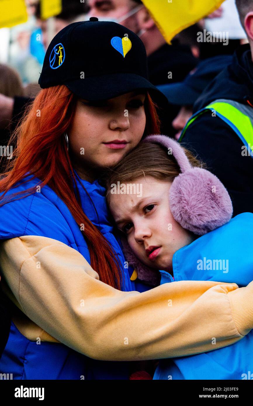 Zwei Mädchen umarmen sich in den Farben der Ukraine vor der Downing Street während proukrainischer Proteste am 2022. März Stockfoto