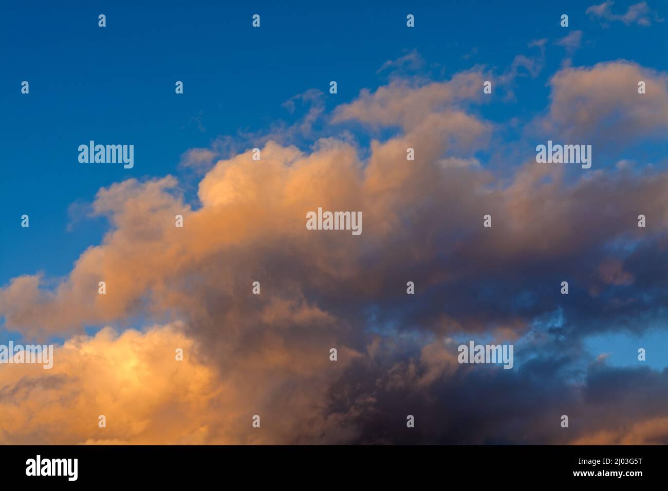 Farbenfrohe, weiche, wispy-orange Wolken vor einem blauen Winterhimmel Stockfoto