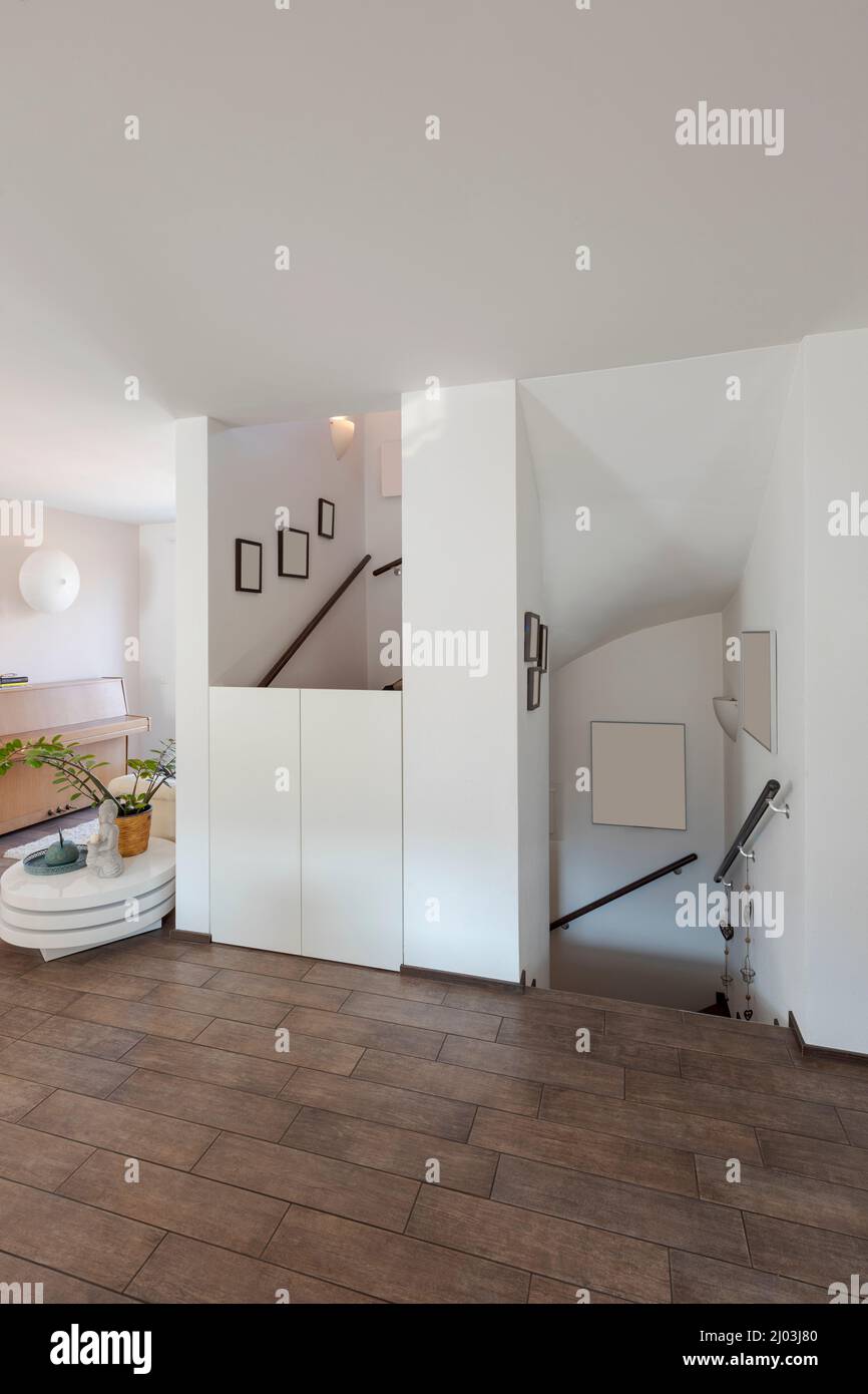 Kleine Treppe in moderner Wohnung mit weißen Wänden und braunem Boden. Du kannst sowohl nach unten als auch nach oben gehen. Niemand drinnen. Stockfoto