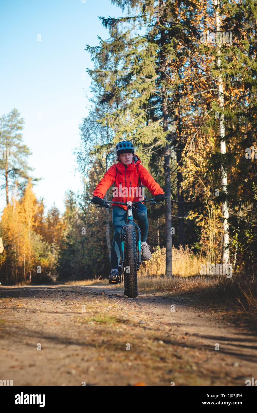 Junge sympathische Dame mit einem schönen realistischen Lächeln, während sie sportlich ist. Radfahrer, die in der wilden Natur Finnlands auf dem Fat Bike reiten. Vuokatti. Cyclin Stockfoto