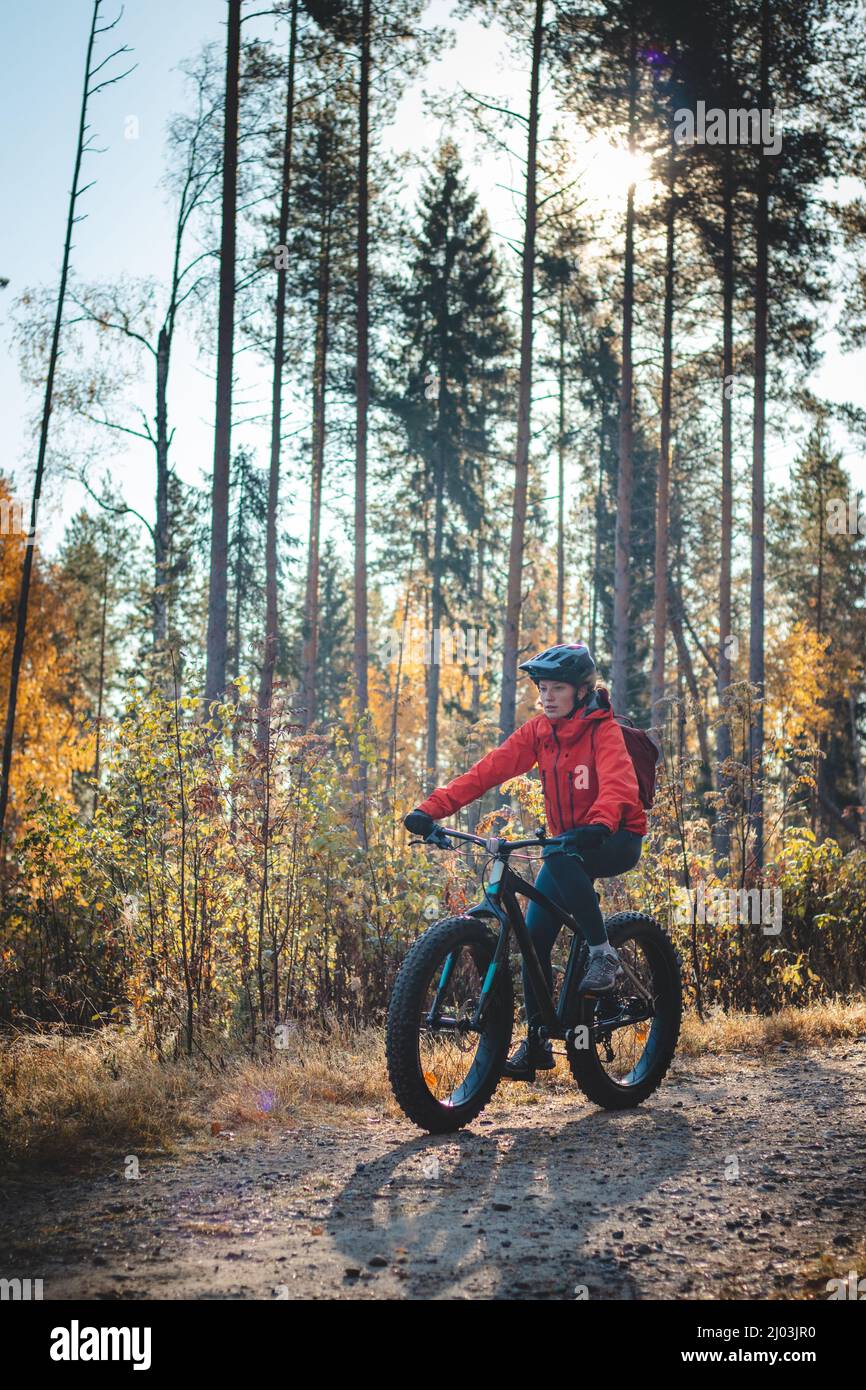 Junge sympathische Dame mit einem schönen realistischen Lächeln, während sie sportlich ist. Radfahrer, die in der wilden Natur Finnlands auf dem Fat Bike reiten. Vuokatti. Cyclin Stockfoto